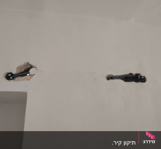 שני חורים בקיר עם צינורות חשמל חשופים